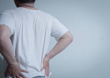 Beyaz gömlekli bir kişinin acı içinde sırt üstü yattığı görülüyor. Rahatsızlık ve üzüntü ifadesi sergiliyor. Bu görüntü sırt ağrısını, yaralanmayı ve tıbbi bakım ihtiyacını temsil ediyor. Bu da onu sağlıkla ilgili içerik ve yazılar için uygun kılıyor.