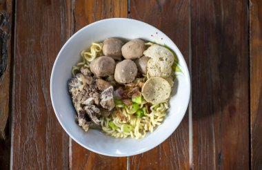 A bowl of meat ball soup with fresh vegetables on the old wooden table