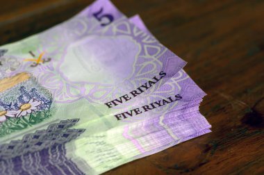 Suudi Arabistan 'dan bir yığın beş riyalist parayı tahta masaya yatırıyor, seçilmiş odak noktası.