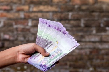 Asyalı çocuklar beş Riyal, Suudi Arabistan para birimi, bağış ve sadaka kavramı ile el ele tutuşuyorlar.