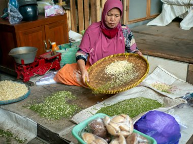 Yogyakarta-Endonezya, 17 Haziran 2023: Bantul, Yogyakarta, Endonezya 'da geleneksel bir pazarda yeşil fasulye satan Müslüman bir kadın