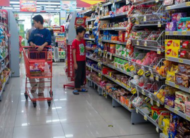 Yogyakarta, Endonezya - 2 Temmuz 2023: Bakkal arabalı iki çocuk Endonezya 'nın Yogyakarta kentindeki bir süpermarket rafından yiyecek seçti.