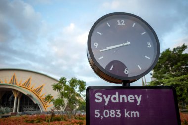 Sydney 'in mor trafik levhası ve Sydney' den 5083 km uzakta mor bir halka açık saat..