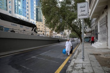 Mecca, Saudi Arabia - June 11, 2024: A couple of Turkey Hajj and Umrah pilgrims walking after buy some gifts in Makkah, Saudi Arabia. Hajj 2024. clipart