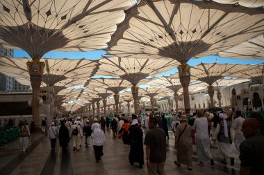 Medine, Suudi Arabistan - 3 Temmuz 2024: Hac ve Umrah hacıları, Medine 'deki Hz. Muhammed Camii' ndeki dev otomatik şemsiyeler altında, diğer adıyla Mescid Nabawi, Suudi Arabistan.