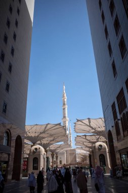 Medine, Suudi Arabistan - 2 Temmuz 2024: Hac ve Umrah hacıları, Suudi Arabistan 'da Mescid Nabawi olarak da bilinen Madinah' taki Hz. Muhammed Camii kapıları ve süpermarketlerin önünde yürüyorlar..