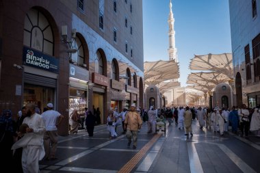 Medine, Suudi Arabistan - 2 Temmuz 2024: Hac ve Umrah hacıları, Suudi Arabistan 'da Mescid Nabawi olarak da bilinen Madinah' taki Hz. Muhammed Camii kapıları ve süpermarketlerin önünde yürüyorlar..