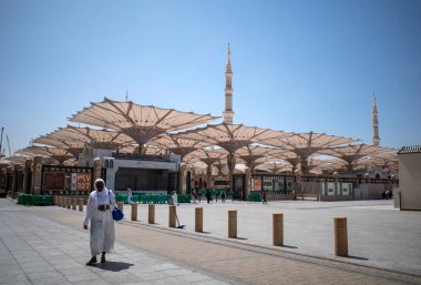 Medine, Suudi Arabistan - 29 Haziran 2024: Suudi Arabistan 'da Mescid Nabawi olarak da bilinen Peygamber Camii' ndeki dev otomatik şemsiyelerin yakınında Afrikalı hacı ve Umrah hacılar.