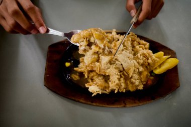 Asyalı bir çocuk eli elektrikli ocakta et kesiyor..