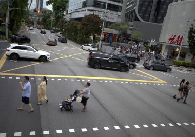 Singapur - 29 Kasım 2024: İnsanlar Orchard Rd Singapur trafiğinde karşıdan karşıya rahatça geçiyor