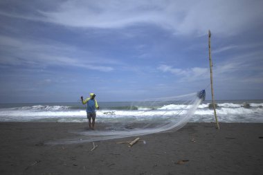 Bir balıkçı, Congot Beach, Kulon Progo, Yogyakarta, Endonezya 'da balık yakalamak için ağ hazırlıyor..