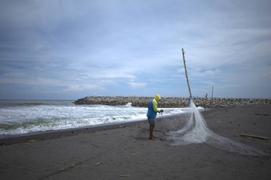 Bir balıkçı, Congot Beach, Kulon Progo, Yogyakarta, Endonezya 'da balık yakalamak için ağ hazırlıyor..