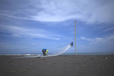 Bir balıkçı, Congot Beach, Kulon Progo, Yogyakarta, Endonezya 'da balık yakalamak için ağ hazırlıyor..