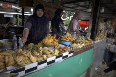 Semarang-Endonezya, 10 Kasım 2024: Bir gorengan satıcısı kadın, kızarmış Cassava, Bakwan Goreng, kızarmış muz, Semarang, Endonezya 'daki geleneksel pazarda sokak yemekleri.