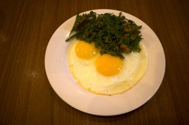 Beyaz tabakta eğreltiotu sebzeli leziz kızarmış yumurta..