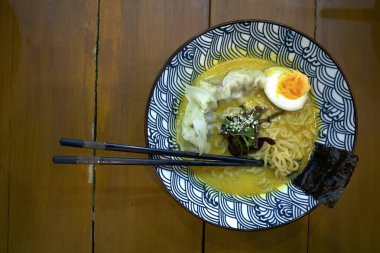 Bir kase erişte, ahşap masada çubuklu Japon yemeği..