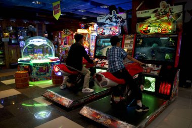 Yogyakarta, Endonezya - 17 Aralık 2024: İki çocuk Yogyakarta, Endonezya 'da bir süpermarkette motosiklet yarışı simülatörü oynuyorlar