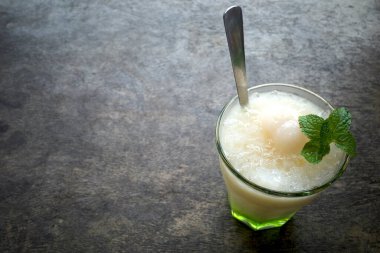 Bir bardak ferahlatıcı limon, nane yaprağı ve buz, ahşap masada..