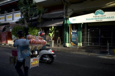 Yogyakarta, Endonezya - 26 Aralık 2024: Beringharjo Market, Yogyakarta 'da bir Gulali şeker satıcısı. Java, Endonezya 'dan geleneksel bir şeker, kırmızı renkli şeker şekeri içeren, çiçek benzeri tasarımlar şeklinde sanatsal şekillendirilmiş.