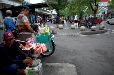 Yogyakarta, Endonezya - 26 Aralık 2024: Endonezya 'nın Yogyakarta kentindeki Malioboro Caddesi' nde geleneksel Cava yemekleri satan yaşlı bir Endonezyalı adam.