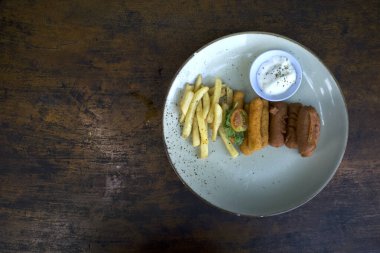 Karışık tabak, çeşitli yemek malzemeleri, patates kızartması, sosis, nugget, ahşap bir tabakta dilimlenmiş domates..
