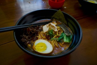 Bir kase erişte, ahşap masada çubuklu Japon yemeği..