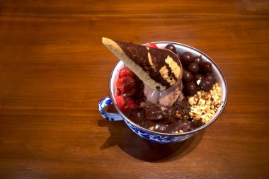 Klasik bir kasede dondurma, koni garnitür, çikolata topları, fındık, puding ve karpuz, ahşap bir masada..