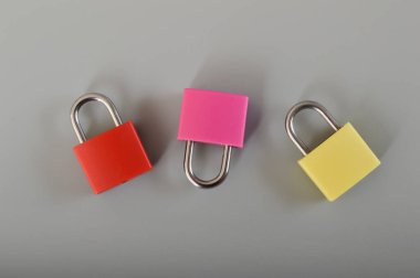 Gri arkaplanda kırmızı, pembe ve sarı asma kilit var..