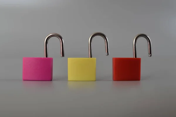 灰色の背景に隔離された赤 ピンク 黄色の南京錠 — ストック写真