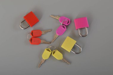 Gri arkaplanda izole edilmiş renkli asma kilitler ve anahtarlar