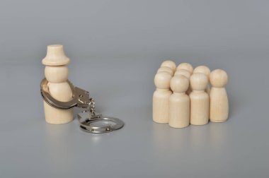 İşçilerin önünde elleri kelepçeli bir mahkum. Yolsuzluk, dolandırıcılık suçu, kara para aklama veya tedarik zinciri dolandırıcılığı.