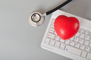 Stetoskop, kırmızı kalp ve bilgisayar klavyesi. Çevrimiçi tıbbi danışma kavramı.