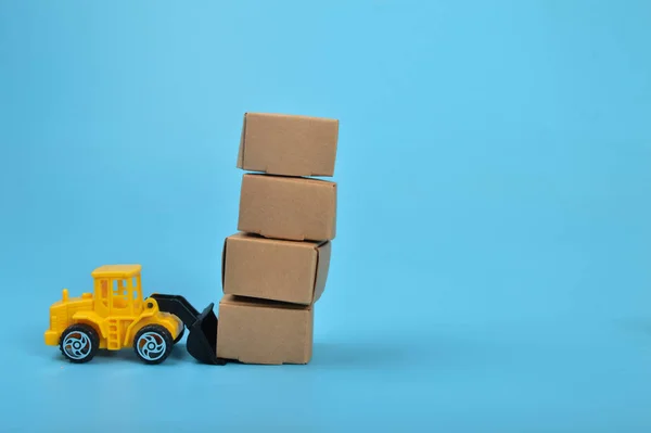 stock image Yellow backhoe with paper boxes isolated on a blue background.