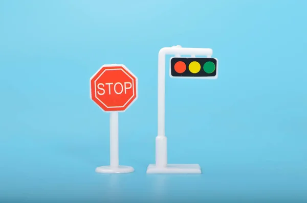 Traffic light toy and stop sign isolated on a blue background.