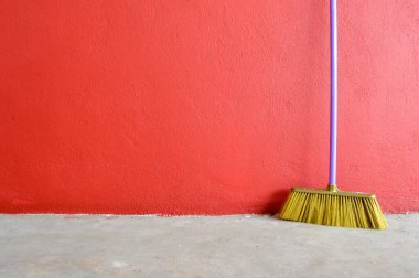Plastik süpürge kırmızı duvara dayanmıştı. Metin için alanı kopyala.