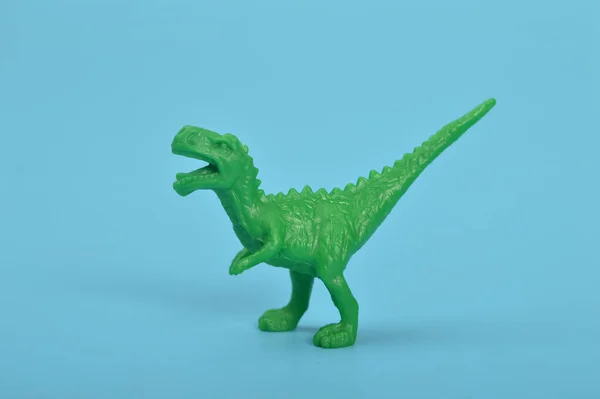 Green T-Rex dinosaur toy isolated on a blue background
