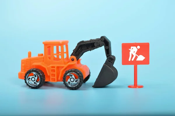 建設現場のおもちゃ掘削機は 人間の労働の重要性と建設業界での機械の使用を表す仕事をする人々のシンボルを伴います — ストック写真