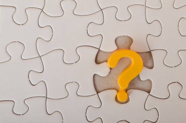 Yapboz arka planında sarı bir soru işareti görüntüsü problem çözme, kafa karışıklığı, çözüm arama ve danışmanlık fikirlerini iletir.