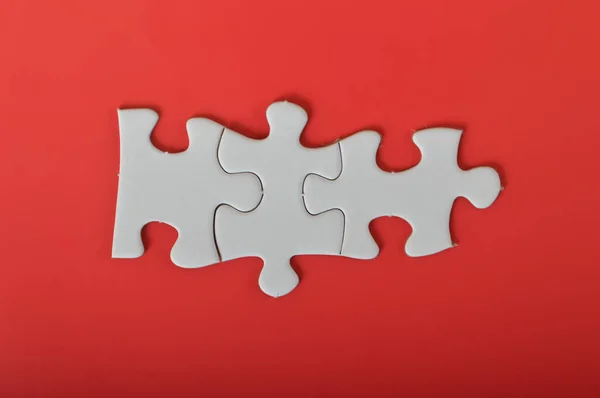 Three puzzle pieces isolated on a red background.