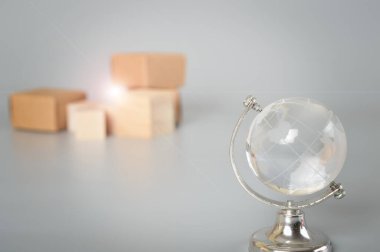 Gri arka planda karton kutular ve dünya küresi. İnternet alışverişi ve e-ticaret dünyası paket teslimatının pürüzsüz entegrasyonu ve küresel nakliye şirketlerini birbirine bağlama konusunda gelişiyor..