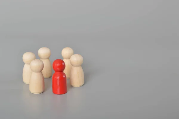 stock image A circle of people surrounds a red person.This depiction represents the essence of business teamwork, showcasing the power of collaboration, team spirit, and collective effort. The wooden figures of people symbolize the strength and unity that arise 