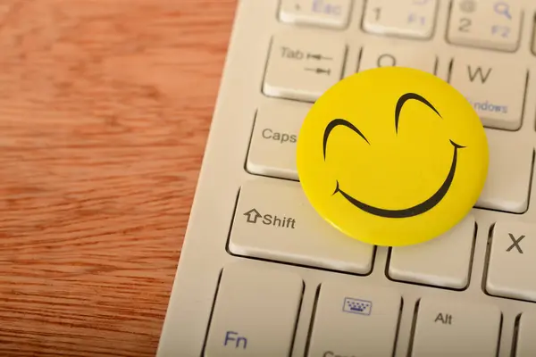 stock image A happy face emoticon on a laptop keyboard represents concepts of customer service evaluation and satisfaction surveys.