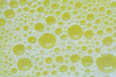 Sarı yıkama sıvısında baloncukların yakın plan görüntüsü kabarcıklı bir zemin oluşturur..