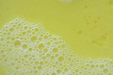 Sarı yıkama sıvısında baloncukların yakın plan görüntüsü kabarcıklı bir zemin oluşturur..