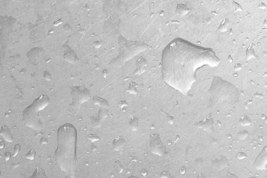 Gri arkaplandaki su damlacıkları. Su damlacıklarıyla kaplı cam bir zemin, suyun içinde kabarcıklar sergiliyor..