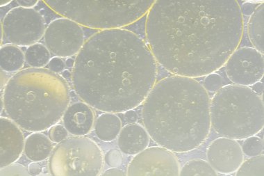 Su yüzeyindeki yağ damlacıkları soyut bir arkaplan oluşturuyor..