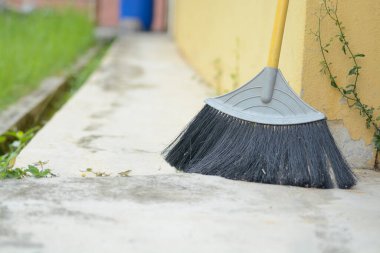 Bir sokak süpürgesi beton bir duvara yaslanıyor..