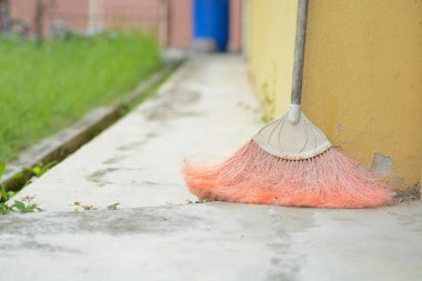 Bir sokak süpürgesi beton bir duvara yaslanıyor..