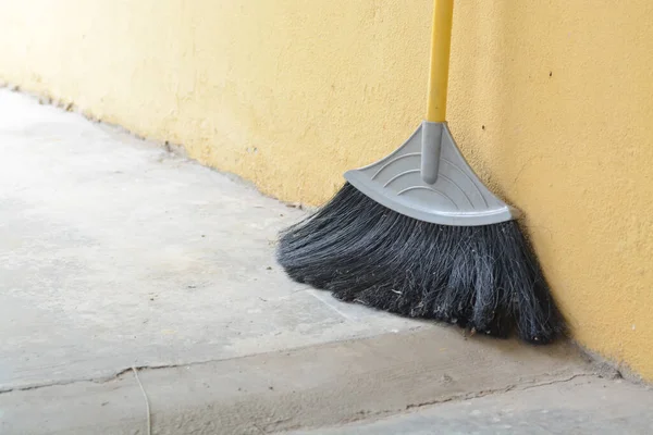 Bir sokak süpürgesi beton bir duvara yaslanıyor..