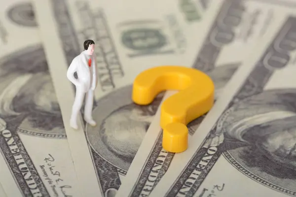 The businessman and the stack of money banknotes, a question mark forming over his head, representing the problem concept